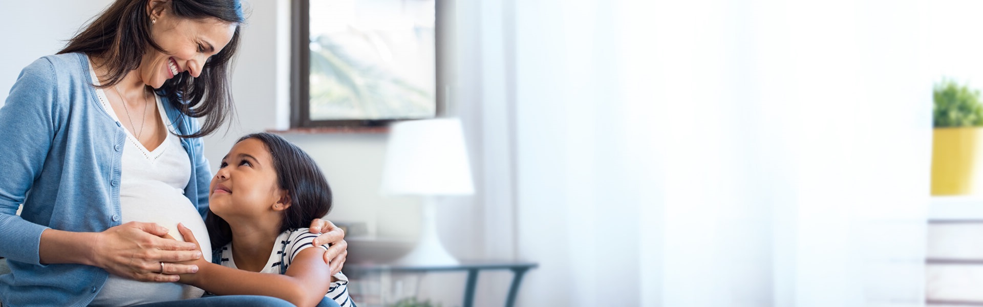 Protección Creciente Madre embarazada que le explica a su hija mayor lo protegidas que están, gracias al seguro de Protección Creciente del Banco Caja Social