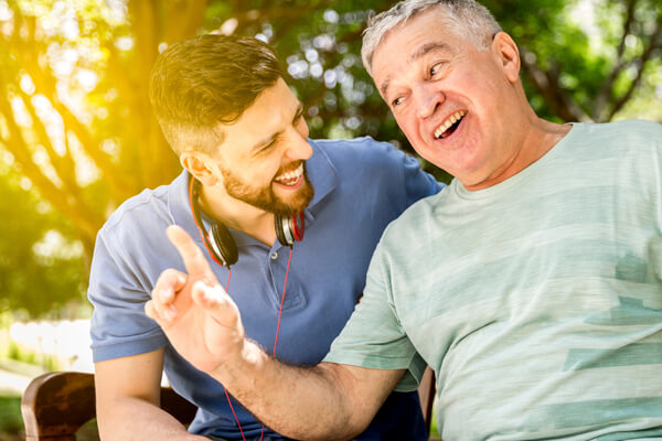 Padre e hijo, disfrutan de una conversación y una linda tarde. El papá le cuenta que se siente tranquilo con su Crédito de Libranza.