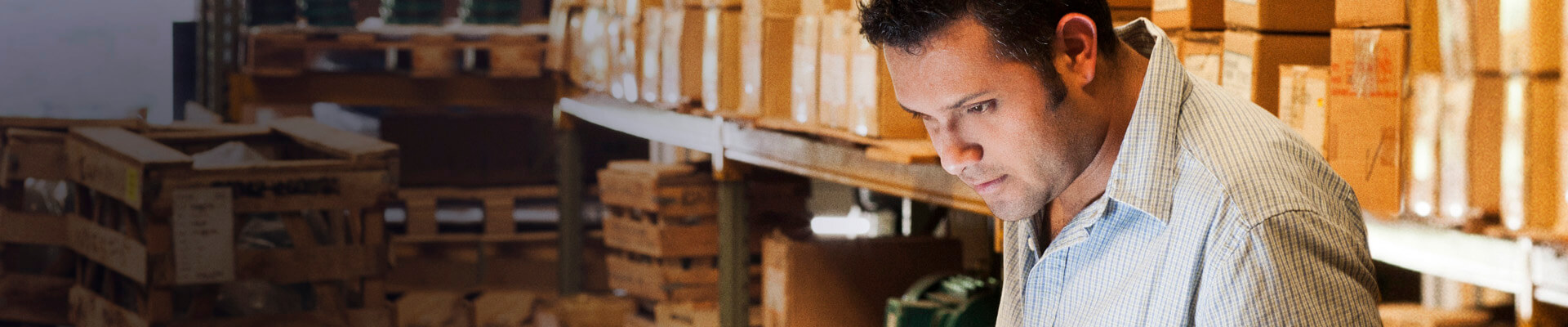 Este hombre  en medio de su bodega, revisa resultados de una exportación . Con sus productos de Cash Management su negocio va sobre ruedas.