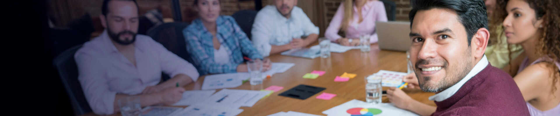 Julián está en reunión. Sonríe porque la Cuenta Corriente Empresarial le ha permitido rendir cuentas de las transacciones con los clientes.